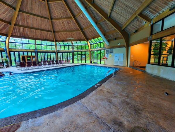 An indoor swimming pool with wooden beams and large windows.