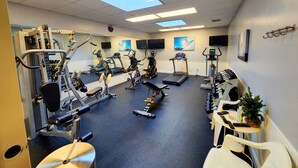 A gym with cardio machines, weight machines, and a mirror wall.