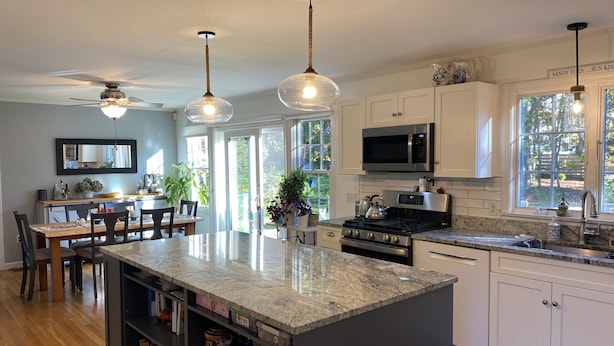 Una cocina moderna con armarios blancos, encimera de granito y una isla central.
