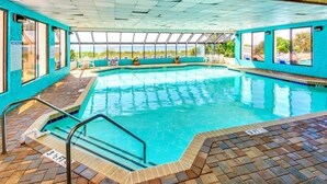 An indoor swimming pool with clear glass walls, a tiled floor, and a view of the outdoors. - Newly Renovated Beachfront Oasis. (Myrtle Beach)