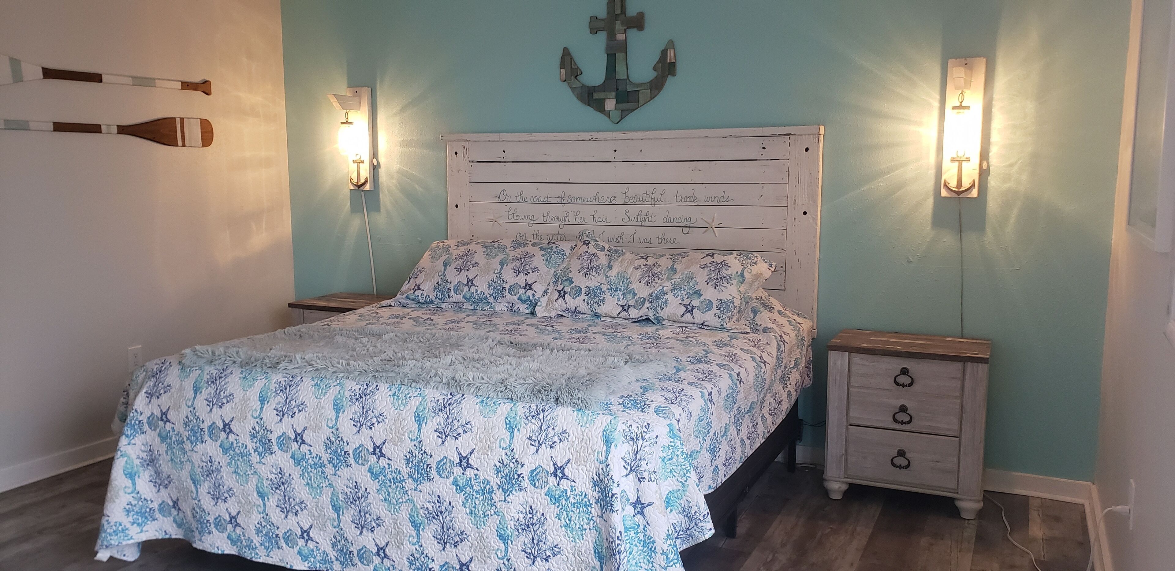A bedroom with a bed, two nightstands, and wall-mounted lights.