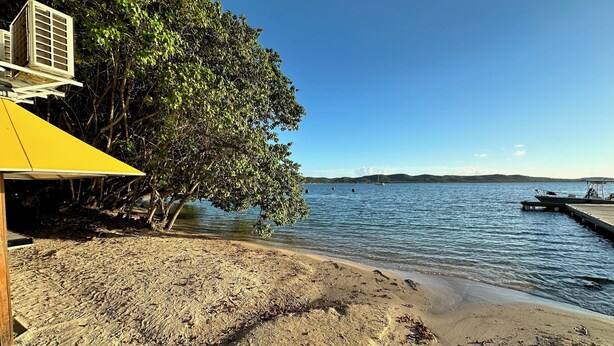 A beach with a yellow structure, a dock, and boats in the water. - Walking distance to Boqueron, private pool, full A/C, sleeps 10 (Boquerón)