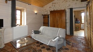 Ein gemütliches Zimmer mit einer Couch, einem kleinen Tisch, einem Heizkörper und einem Holzschrank.