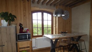Eine rustikale Küche mit Holzwänden, einem großen Fenster, einer Mikrowelle und einem Tisch mit Hockern.