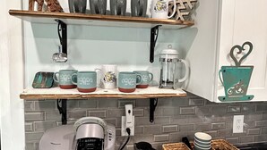 Et køkken med kaffedekoration, inklusive et skilt med kaffe, kaffekopper og en Keurig kaffemaskine.