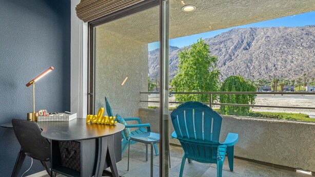 Ein Balkon mit Tisch und Stühlen, einer Lampe und Blick auf die Berge.
