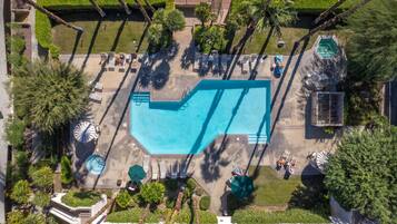 An aerial view of a resort with a swimming pool, sun loungers, and palm trees.