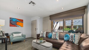 Ein modernes Wohnzimmer mit einer Couch, Hocker und einem Gemälde an der Wand.