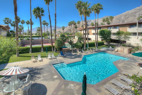 Relax by the pool surrounded by palm trees and a mountain backdrop.