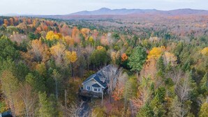 Una casa rodeada por un bosque con follaje otoñal.