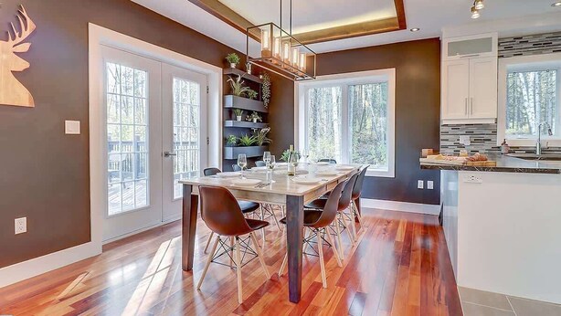 Una cocina moderna con zona de comedor, que incluye una mesa de madera, sillas y estanterías empotradas con plantas.