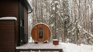 En stuga av trä med en stor, rund dörr, en träbänk och en veranda täckt av snö.