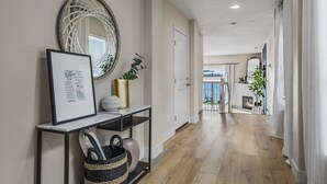 Un couloir agrémenté d’une console, d’œuvres d’art encadrées, d’un panier en osier et d’un miroir décoratif.