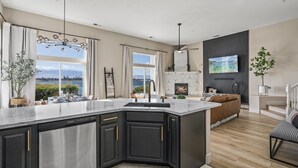 Une cuisine moderne dotée d’un grand îlot central, d’une cheminée et offrant une vue sur l’extérieur.