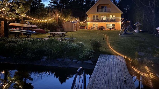 Una casa con terraza, un muelle pequeño y un estanque.