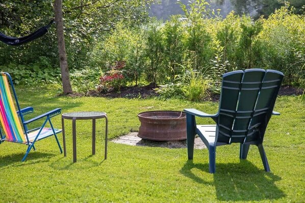 Un jardin avec deux chaises, une petite table et un foyer.