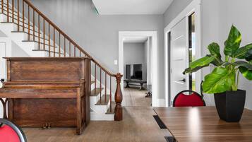 A modern interior with a wooden staircase, a dining area with a table and chairs, and a large potted plant.