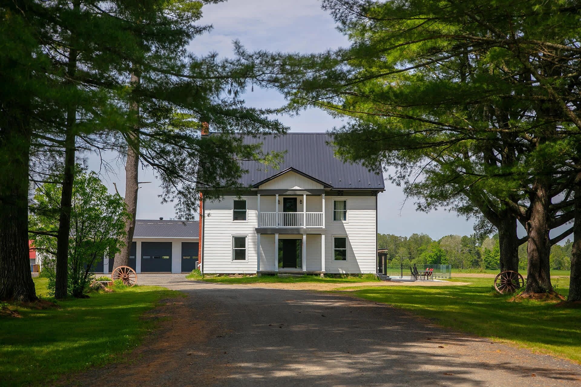 Een tweelaags huis met een veranda, omringd door bomen.