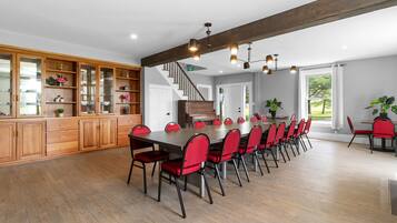 Un comedor amplio con una mesa larga y sillas rojas, armarios de madera y un piano.