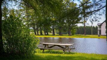 A picnic table by a calm lake surrounded by trees.