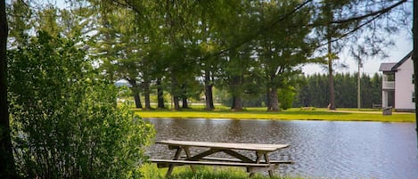 A picnic table by a calm lake surrounded by trees.