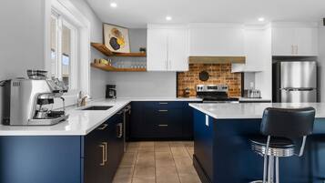 A modern kitchen with a coffee machine, a toaster, and a refrigerator.