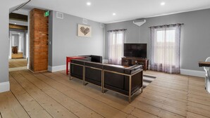 A spacious room with a wooden floor, a brick accent wall, a flat-screen TV, and a sofa. - Access to the river - Spa - Inground pool (Cookshire-Eaton)