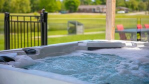 A hot tub with a view of a grassy area and a fence. - Access to the river - Spa - Inground pool (Cookshire-Eaton)