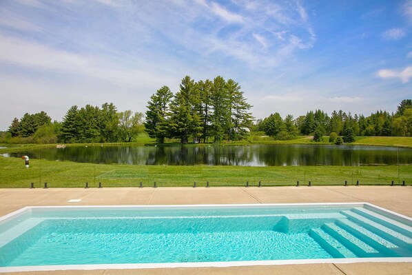 A swimming pool with a clear view of a lake and trees in the background.