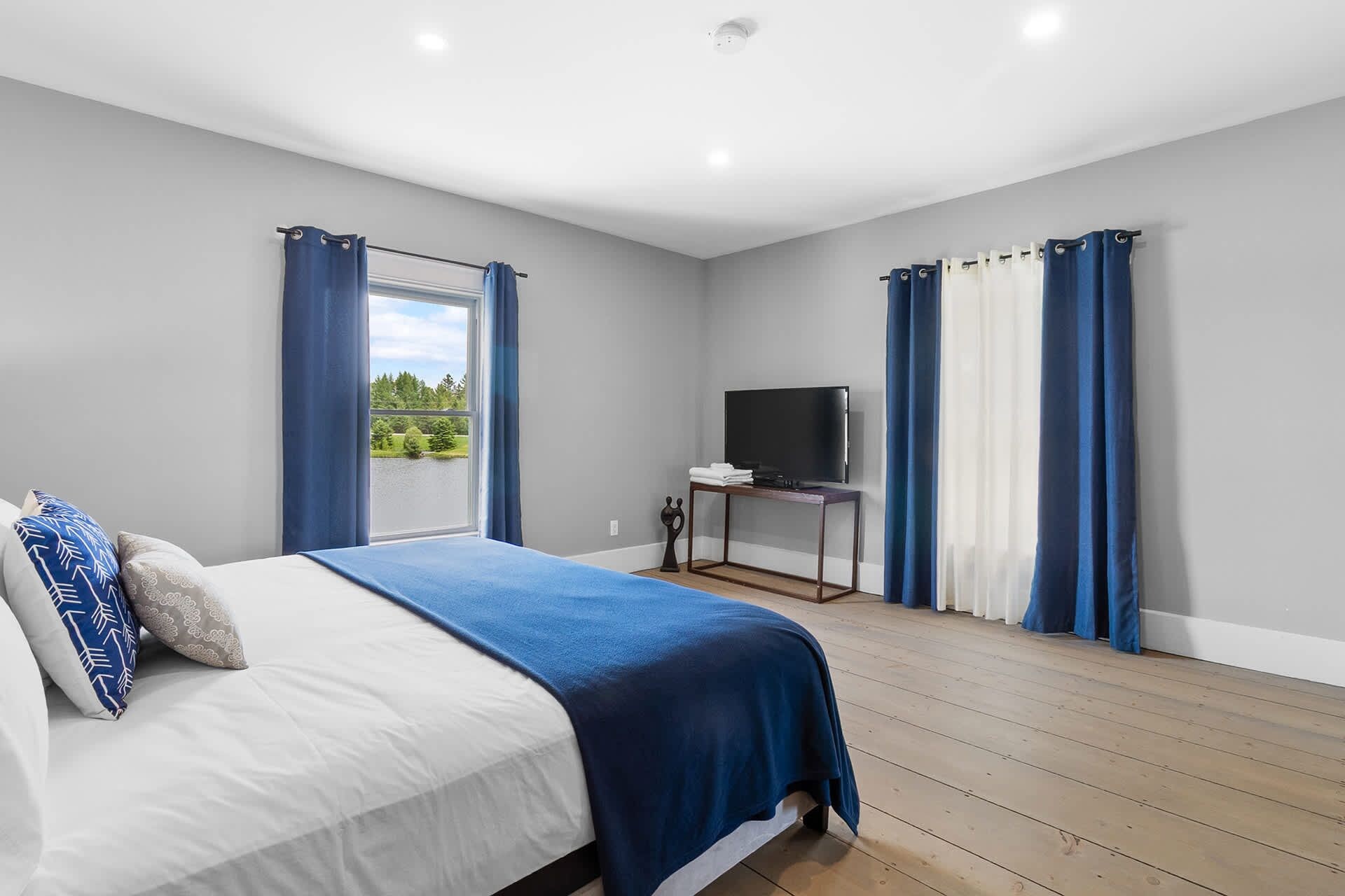 Une chambre à coucher avec un lit, un téléviseur posé sur un meuble et des rideaux.