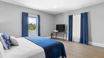 Une chambre à coucher avec un lit, un téléviseur posé sur un meuble et des rideaux.