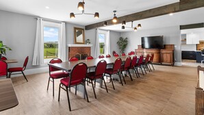 A spacious dining area with a long table and red chairs, a fireplace, and a kitchen area with cabinets and a TV. - Access to the river - Spa - Inground pool (Cookshire-Eaton)