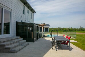 Una casa moderna con un patio, mobiliario exterior y una piscina.