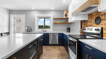 Una cocina moderna con una isla grande, electrodomésticos integrados y vistas por una ventana.