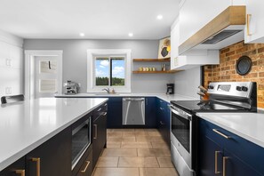 A modern kitchen with a large island, built-in appliances, and a view through a window.
