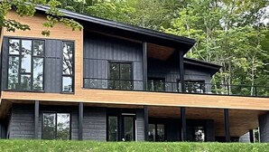 A modern two-story house with a wooden deck and large windows. - Mont Owl's Head - Sauna - Spa - Inground Pool (Mansonville)