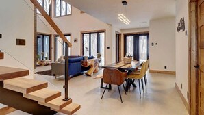 A modern interior with a staircase, a dining area, and a living room with a blue sofa and a wooden coffee table. - Mont Owl's Head - Sauna - Spa - Inground Pool (Mansonville)