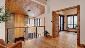 A spacious living area with wooden floors, a high ceiling, and large windows. - Mont Owl's Head - Sauna - Spa - Inground Pool (Mansonville)