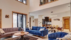 A spacious living area with a sofa, a blue armchair, and a dining table. - Mont Owl's Head - Sauna - Spa - Inground Pool (Mansonville)