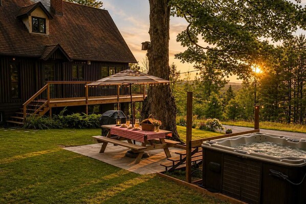 A wooden deck with a picnic table, a hot tub, and a large tree.