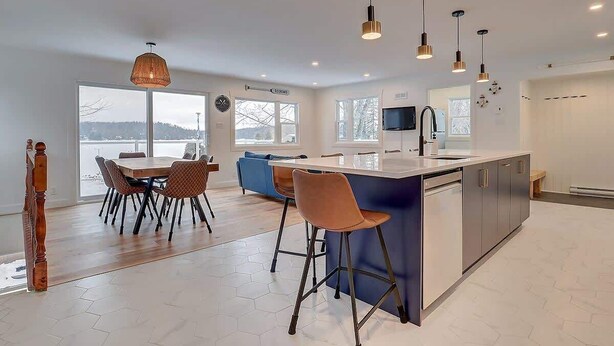 Uma cozinha moderna com ilha central, banquetas e iluminação pendente.