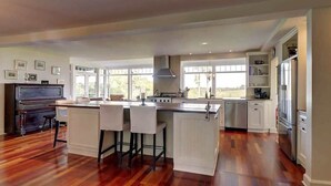A spacious kitchen with a central island, wooden flooring, and large windows. - Brome Lake - Inground Pool - Spa - Lumen (Knowlton)