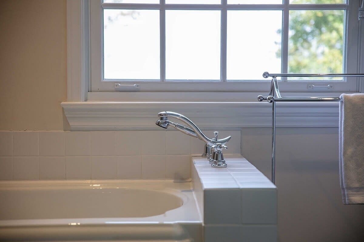 A bathroom with a bathtub, a window, and a towel rack.
