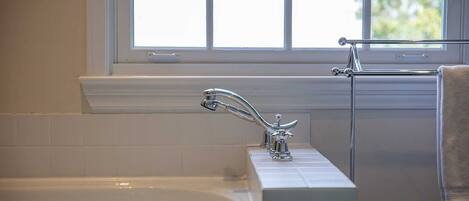 A bathroom with a bathtub, a window, and a towel rack.