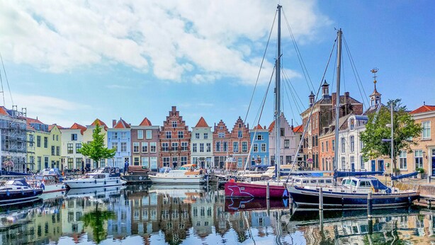 Un canal bordé de bateaux à quai, entouré de bâtiments aux couleurs vives et à l’architecture traditionnelle.