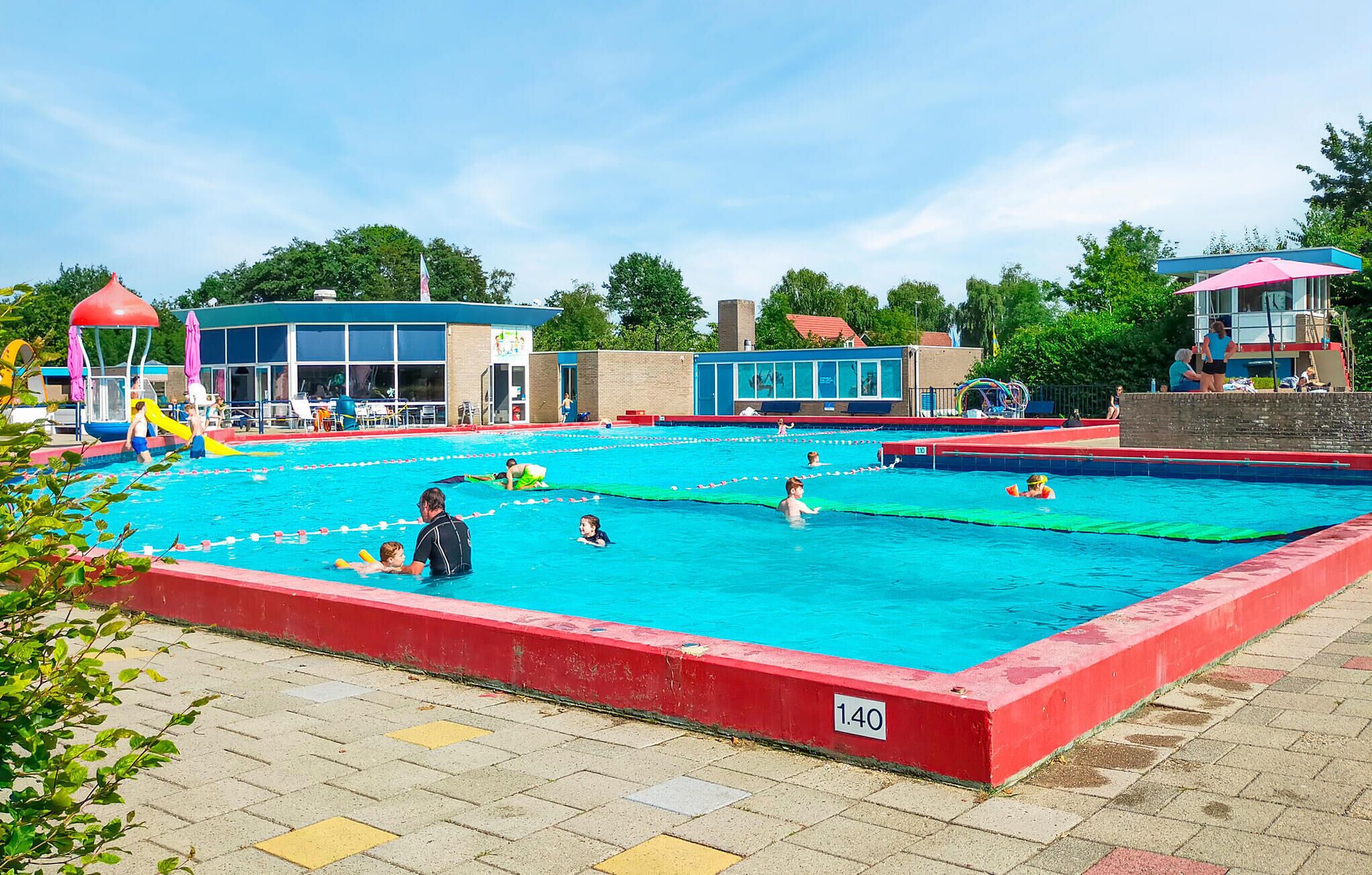 Una piscina con varias pistas de natación, una torre de salvavidas y un vestuario.
