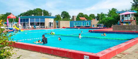 Una piscina con varias pistas de natación, una torre de salvavidas y un vestuario.