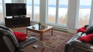 A living room with a large flat-screen TV, leather sofas, a wooden coffee table, and a patterned rug. - Owl's Head - Inground Pool - Spa - View - Méridien (Mansonville)