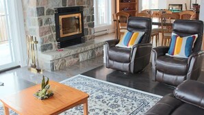 A living room with leather armchairs, a wooden coffee table, and a stone fireplace. - Owl's Head - Inground Pool - Spa - View - Méridien (Mansonville)