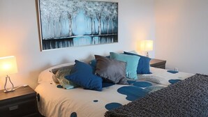 A bedroom with a bed, pillows, a blanket, a nightstand, a lamp, and a painting on the wall. - Owl's Head - Inground Pool - Spa - View - Méridien (Mansonville)